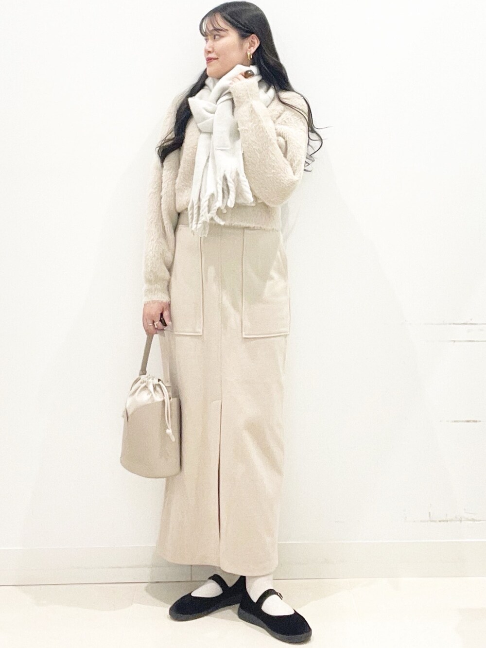 ブラック系のその他シューズ、ベージュ系のスカート、ベージュ系のハンドバッグを着用したレディースの秋コーディネートの2枚目の写真