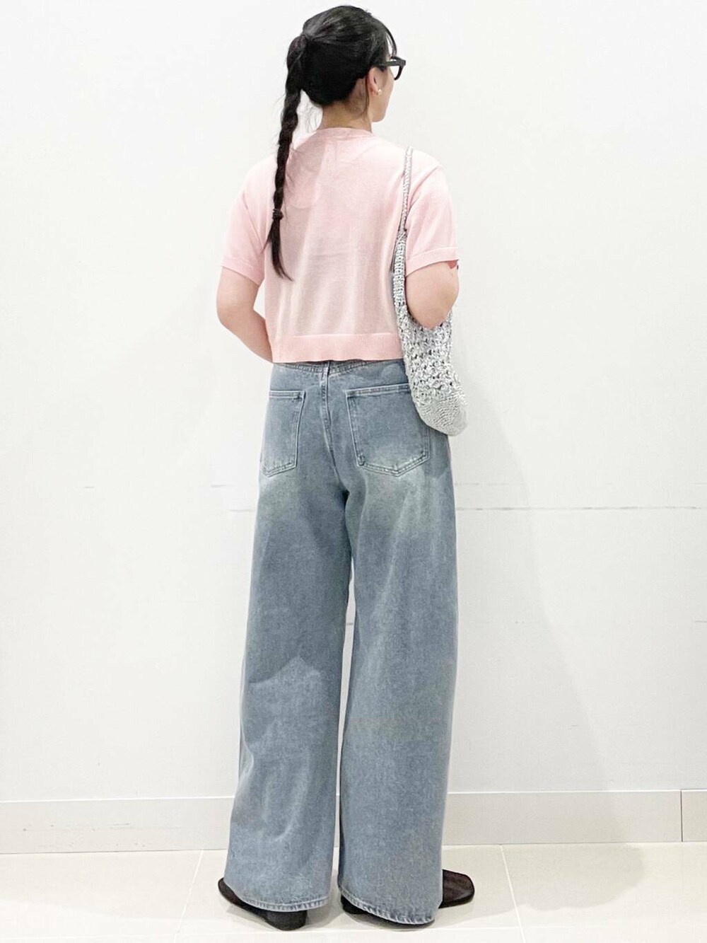 シルバー系のハンドバッグ、ブラック系のパンプス、ブルー系のデニムパンツを着用したレディースの夏コーディネートの5枚目の写真