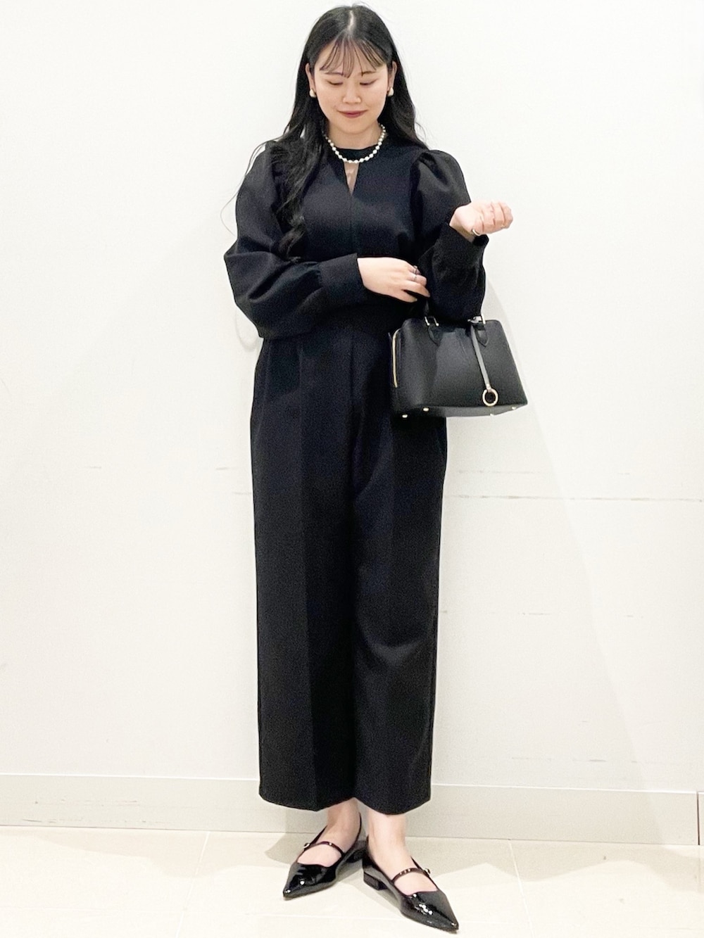 ブラック系のパンプス、ブラック系のハンドバッグ、ブラック系のつなぎ/オールインワンを着用したレディースの冬コーディネートの4枚目の写真