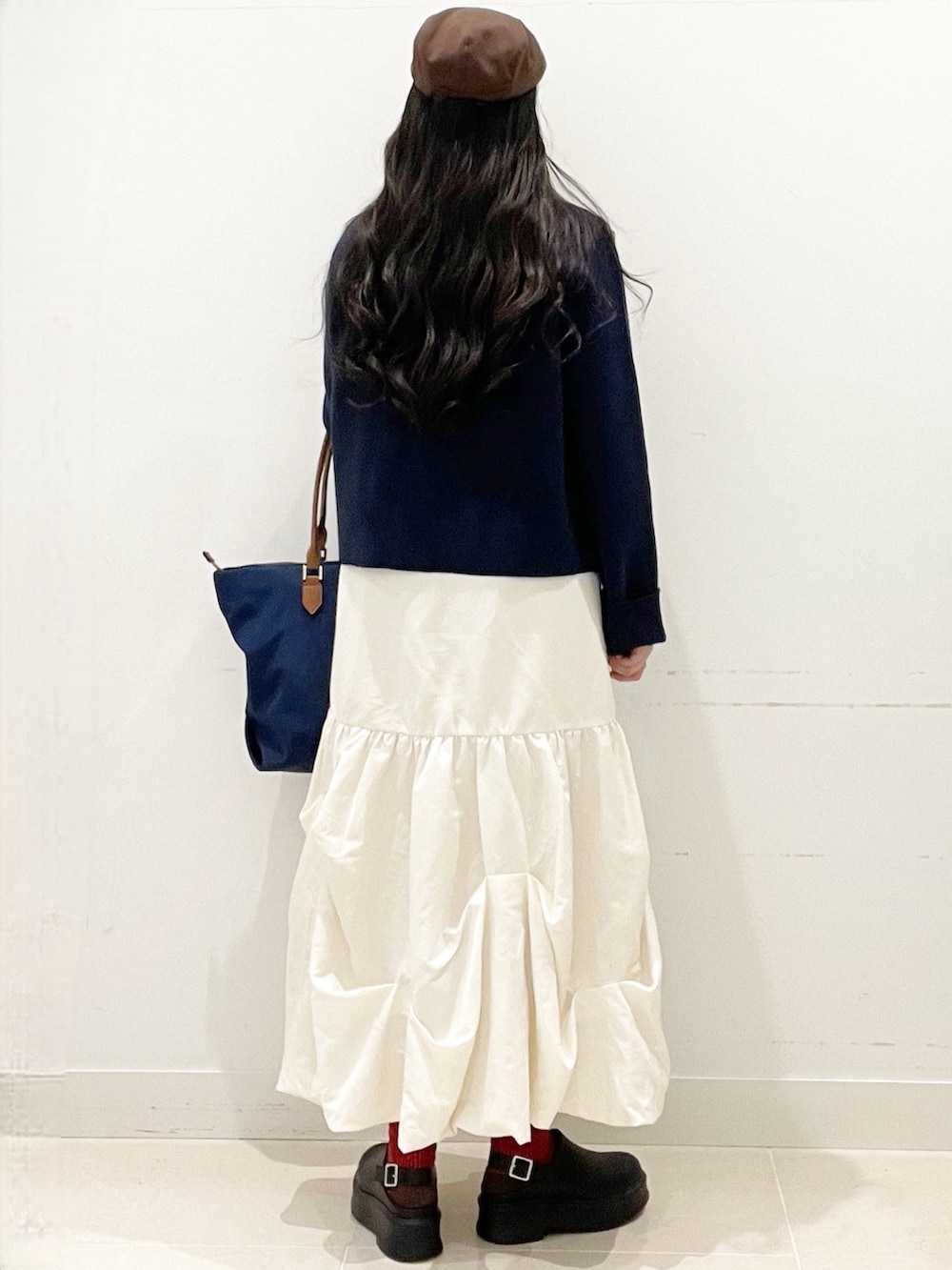 ブラック系のその他シューズ、ホワイト系のスカート、ブルー系のビジネスバッグを着用したレディースの冬コーディネートの5枚目の写真