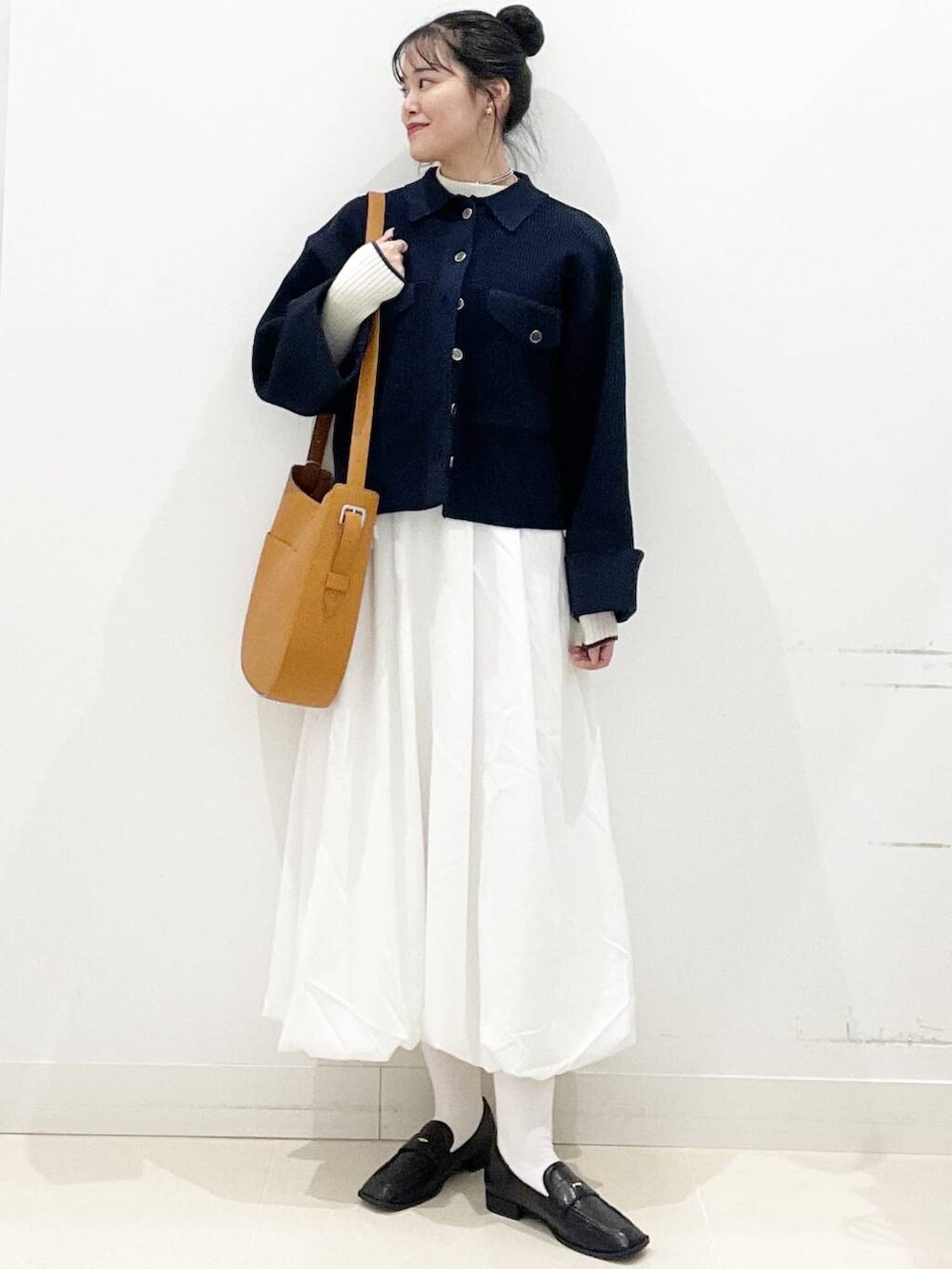 ホワイト系のスカート、ブラウン系のショルダーバッグ、ブラック系のローファーを着用したレディースの冬コーディネートの2枚目の写真