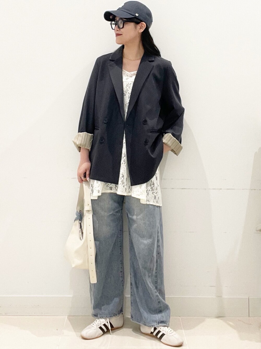 ホワイト系のスニーカー、ブルー系のデニムパンツ、ホワイト系のキャミソールを着用したレディースの春コーディネートの2枚目の写真