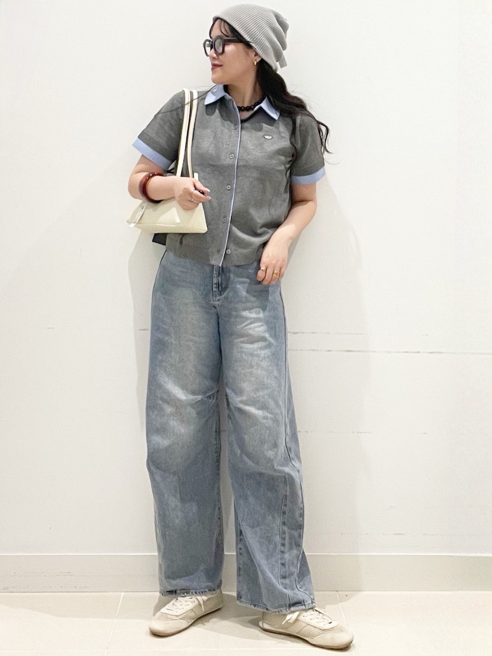ブルー系のデニムパンツ、グレー系のカーディガン/ボレロ、ホワイト系のショルダーバッグを着用したレディースの春コーディネートの2枚目の写真