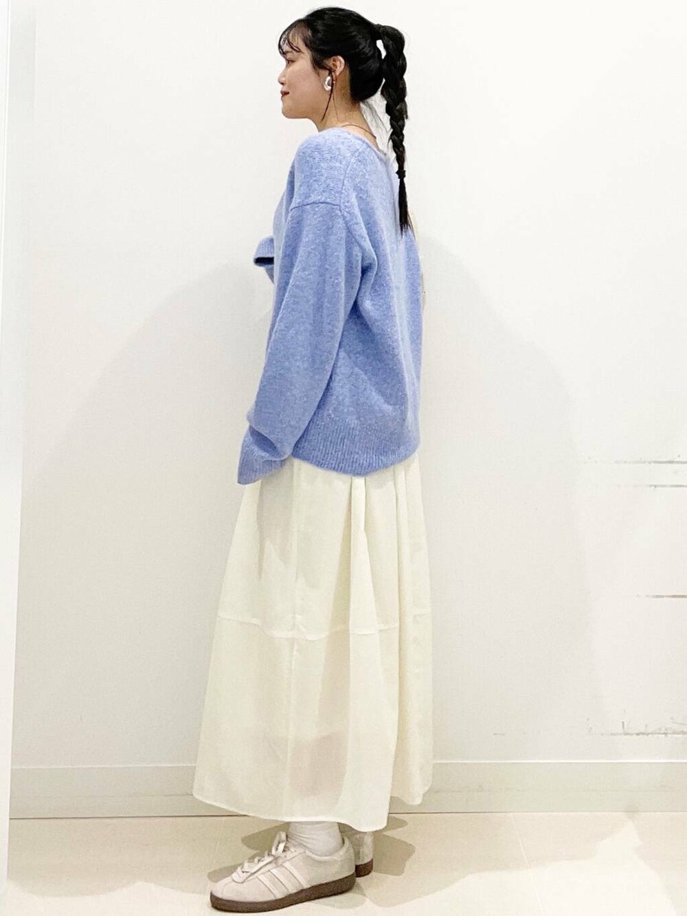 ホワイト系のスニーカー、ブルー系のニット/セーター、ベージュ系のショルダーバッグを着用したレディースの春コーディネートの6枚目の写真