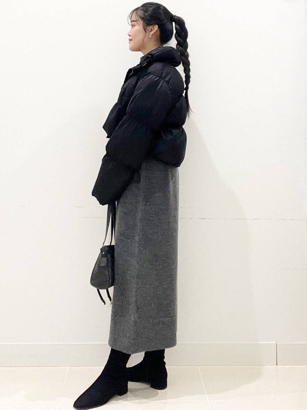 ブラック系のダウンジャケット/コート、ブラック系のブーツ、グレー系のワンピースを着用したレディースの冬コーディネートの5枚目の写真