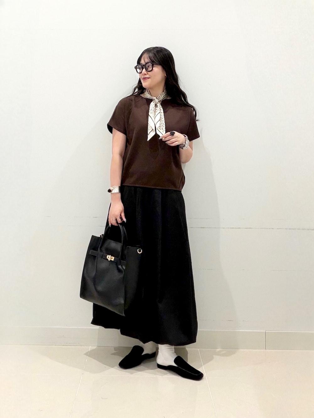 ブラウン系のTシャツ/カットソー、ブラック系のスカート、ブラック系のトートバッグを着用したレディースの秋コーディネートの3枚目の写真