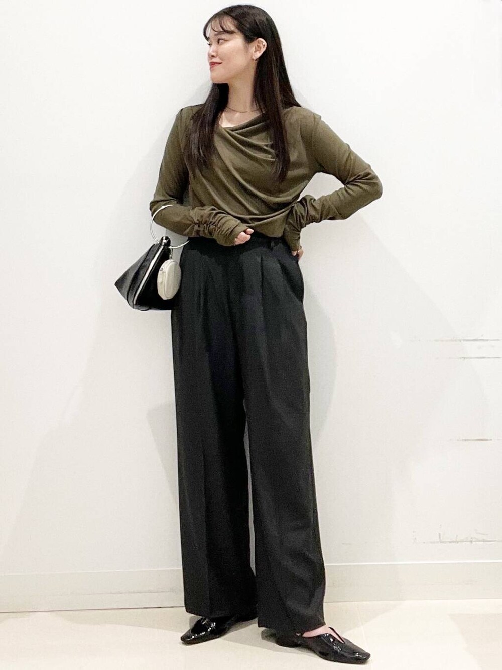 グレー系のその他パンツ、ブラック系のパンプス、ブラック系のハンドバッグを着用したレディースの春コーディネートの2枚目の写真