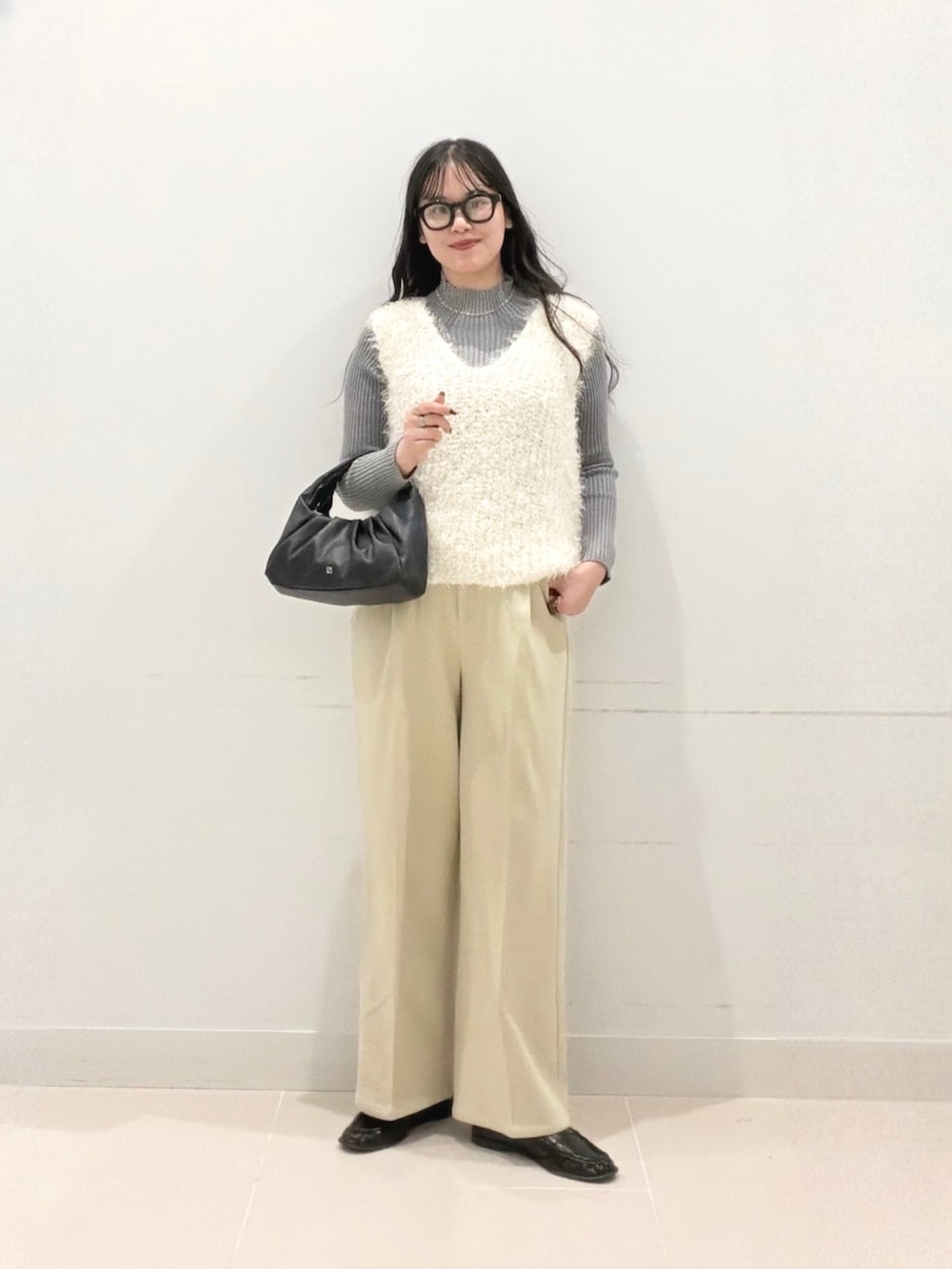 グレー系のニット/セーター、ベージュ系のその他パンツ、ホワイト系のベストを着用したレディースの秋コーディネートの2枚目の写真