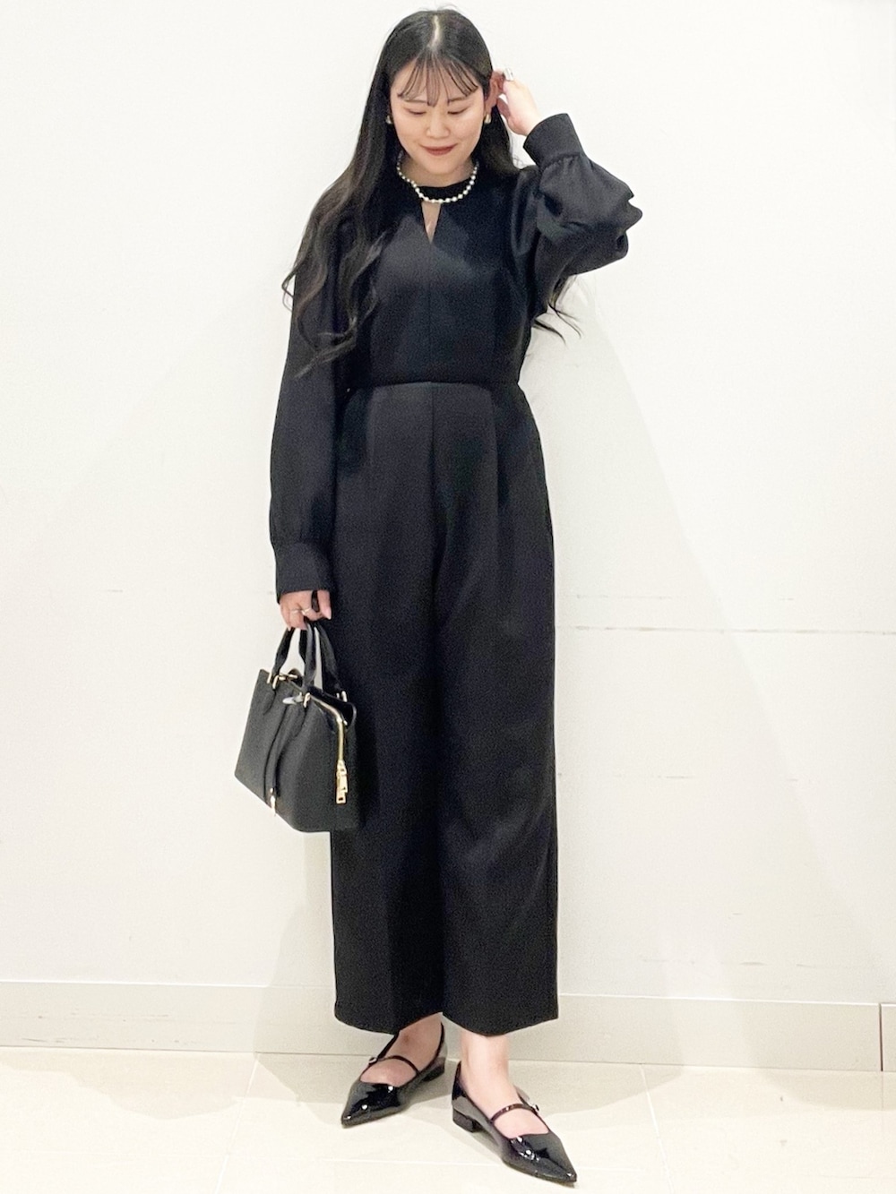 ブラック系のパンプス、ブラック系のハンドバッグ、ブラック系のつなぎ/オールインワンを着用したレディースの冬コーディネートの3枚目の写真