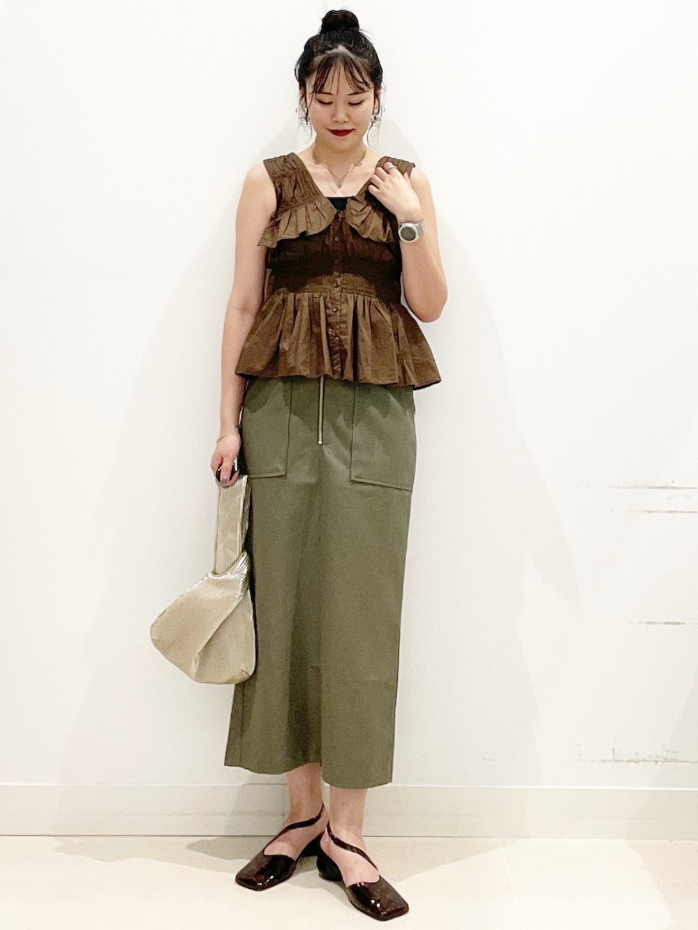 グリーン系のスカート、ブラック系のキャミソール、ゴールド系のハンドバッグを着用したレディースの夏コーディネートの5枚目の写真