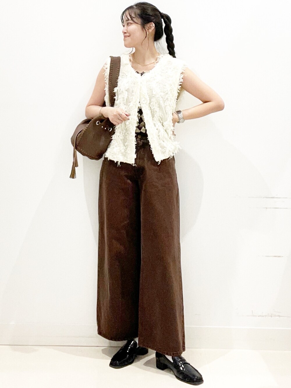 ブラック系のローファー、ブラウン系のショルダーバッグ、ブラウン系のデニムパンツを着用したレディースの夏コーディネートの2枚目の写真