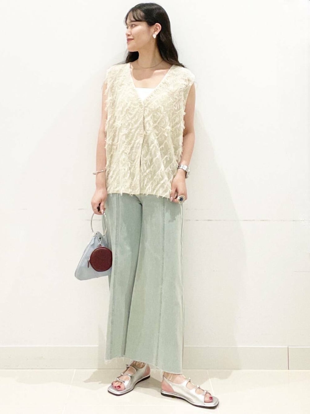 ブルー系のハンドバッグ、ホワイト系のキャミソール、シルバー系のサンダルを着用したレディースの夏コーディネートの2枚目の写真