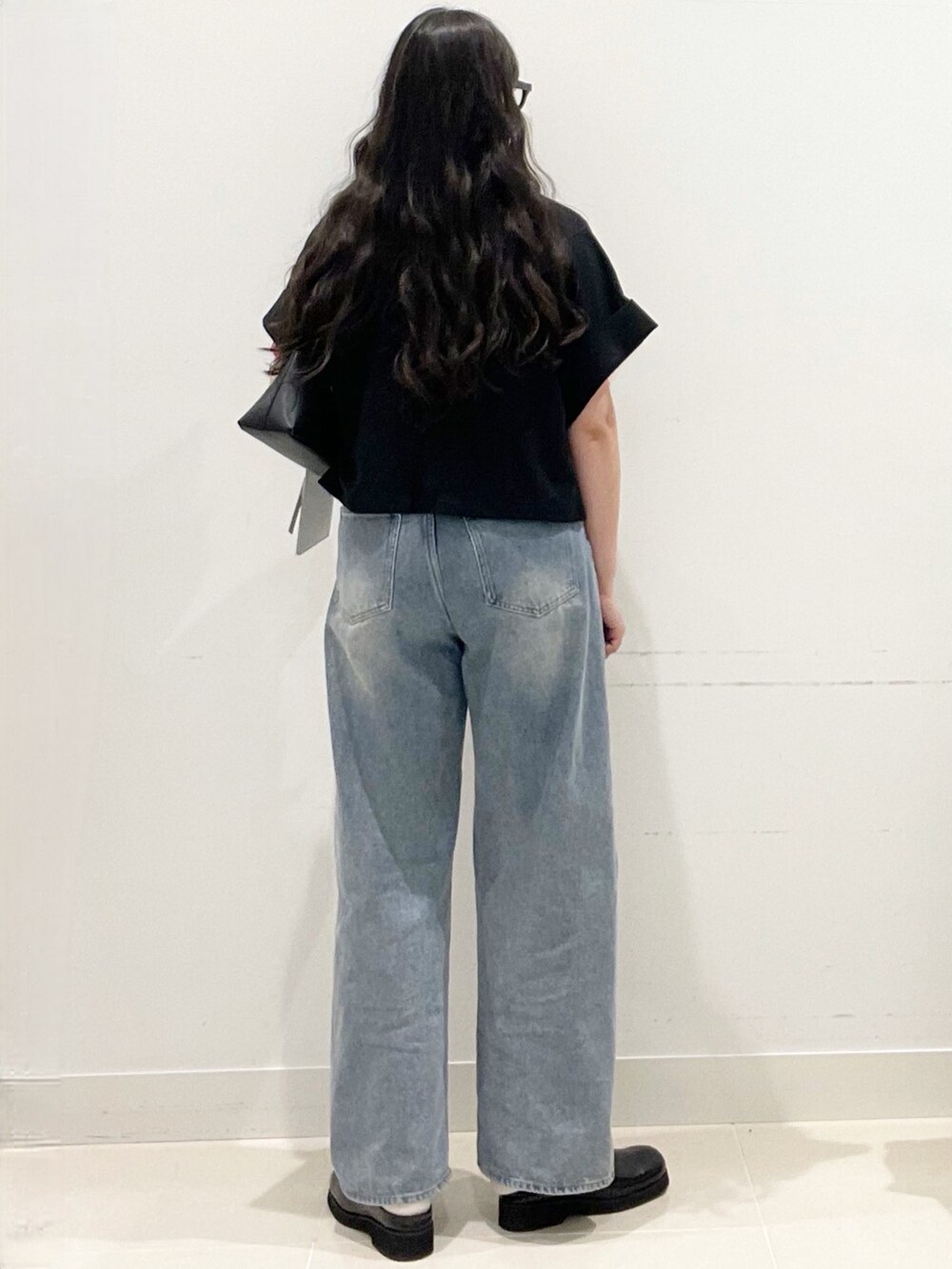 ブラック系のサンダル、ブルー系のデニムパンツ、ブラック系のショルダーバッグを着用したレディースの春コーディネートの4枚目の写真