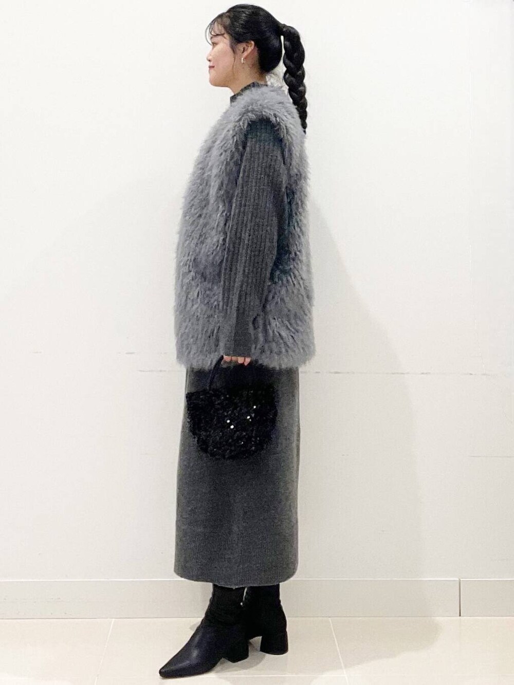 ブラック系のショルダーバッグ、グレー系のベスト、ブラック系のブーツを着用したレディースの冬コーディネートの5枚目の写真