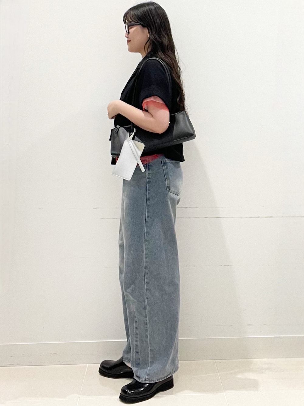 ブラック系のサンダル、ブルー系のデニムパンツ、ブラック系のショルダーバッグを着用したレディースの春コーディネートの3枚目の写真