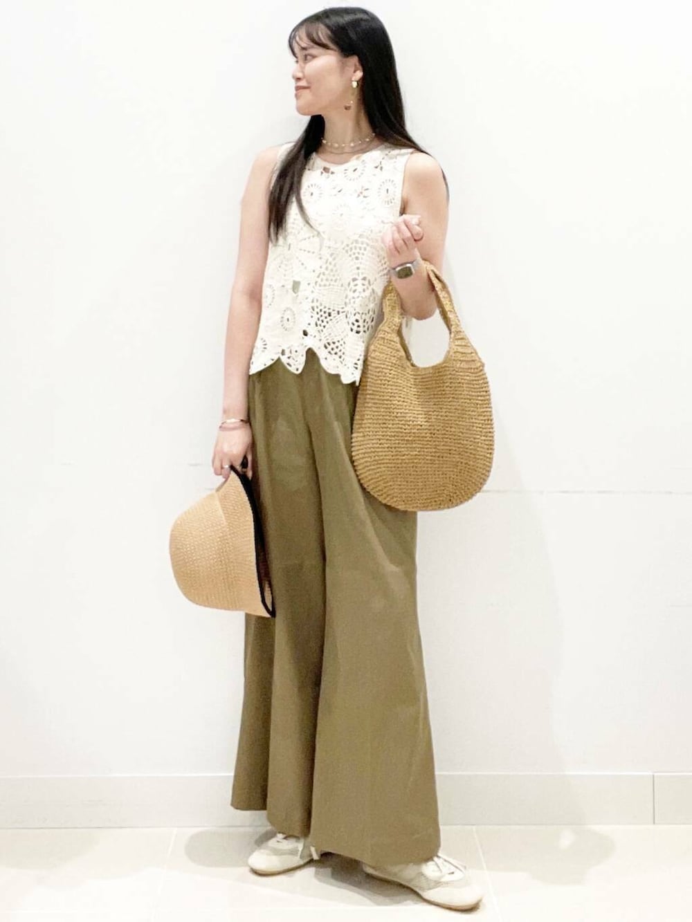 イエロー系のトートバッグ、ホワイト系のキャミソール、ホワイト系のベストを着用したレディースの夏コーディネートの4枚目の写真