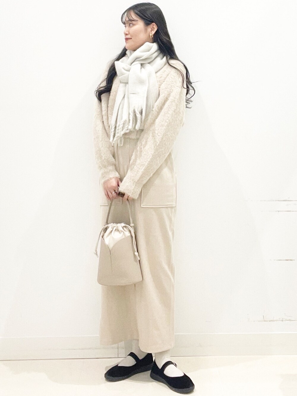 ブラック系のその他シューズ、ベージュ系のスカート、ベージュ系のハンドバッグを着用したレディースの秋コーディネートの3枚目の写真