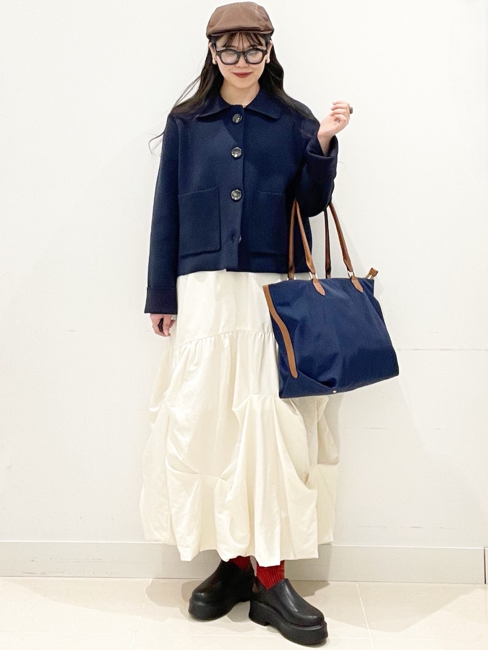 ブラック系のその他シューズ、ホワイト系のスカート、ブルー系のビジネスバッグを着用したレディースの冬コーディネートの3枚目の写真