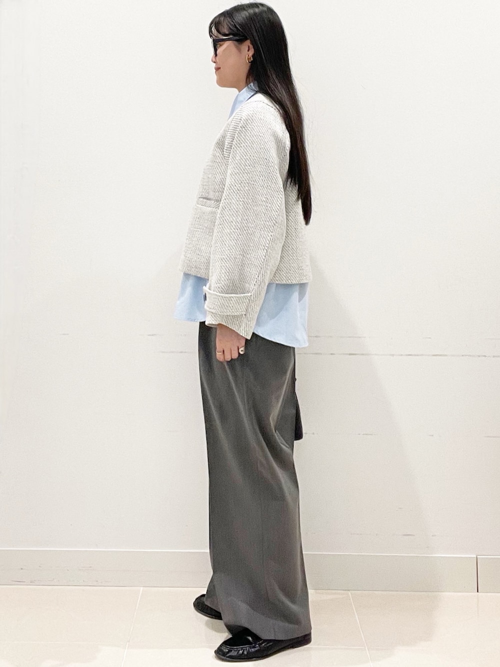 グレー系のスラックス、ブラック系のハンドバッグ、ブルー系のシャツ/ブラウスを着用したレディースの春コーディネートの4枚目の写真