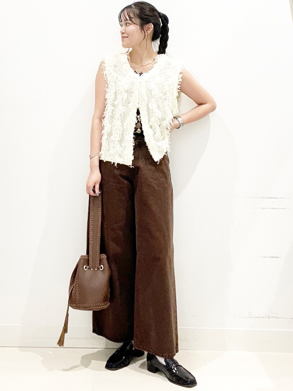 ブラック系のローファー、ブラウン系のショルダーバッグ、ブラウン系のデニムパンツを着用したレディースの夏コーディネートの3枚目の写真