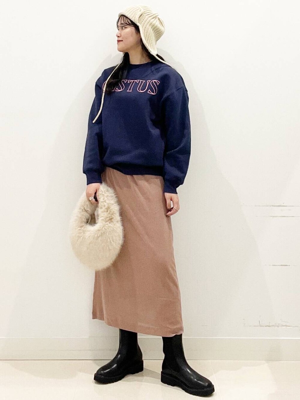 ベージュ系のハンドバッグ、ブラック系のブーツ、ピンク系のスカートを着用したレディースの秋コーディネートの4枚目の写真