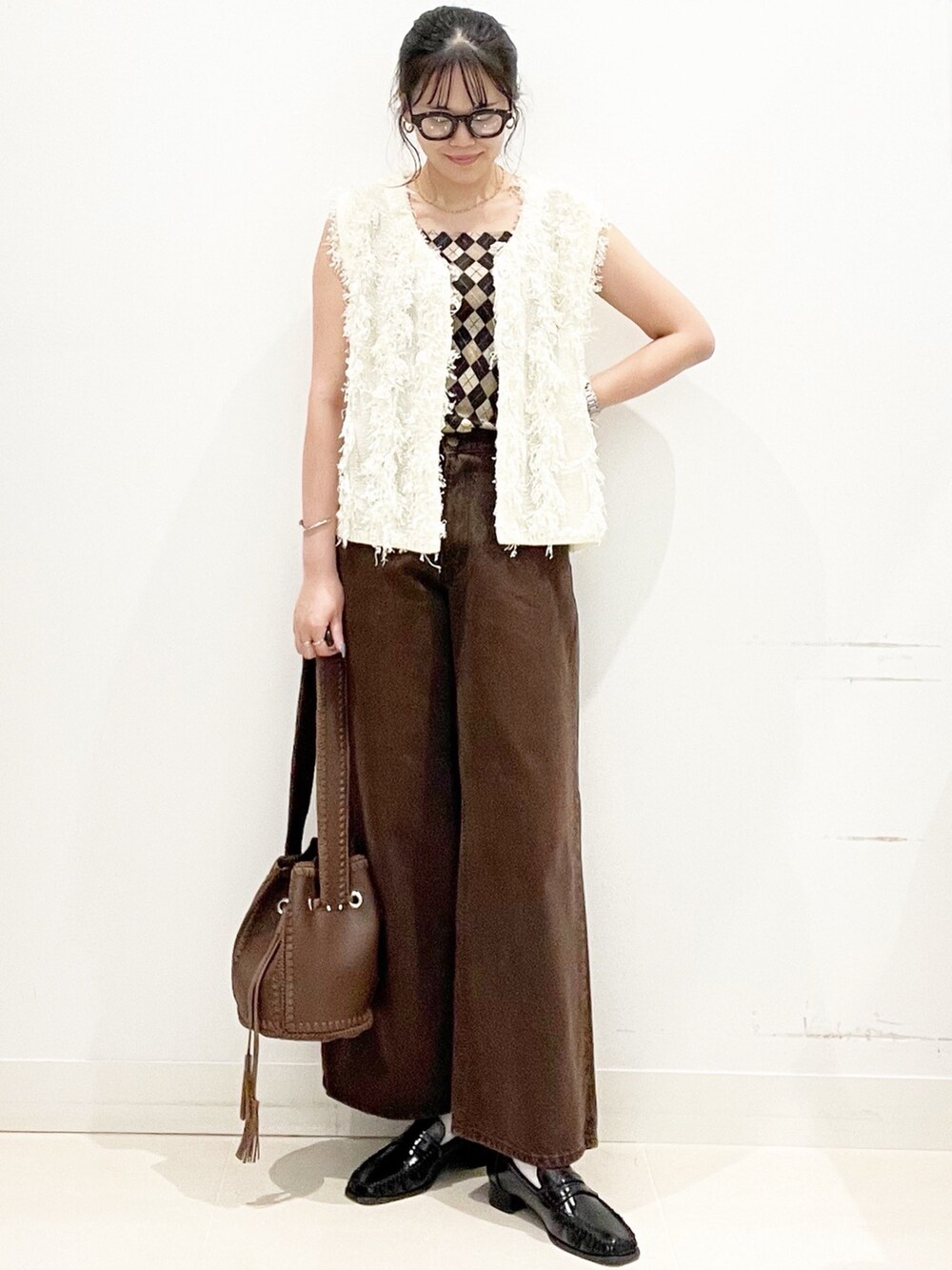 ブラック系のローファー、ブラウン系のショルダーバッグ、ブラウン系のデニムパンツを着用したレディースの夏コーディネートの5枚目の写真