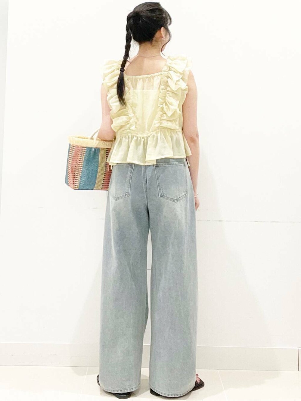 ホワイト系のキャミソール、ブルー系のデニムパンツ、ベージュ系のショルダーバッグを着用したレディースの夏コーディネートの5枚目の写真