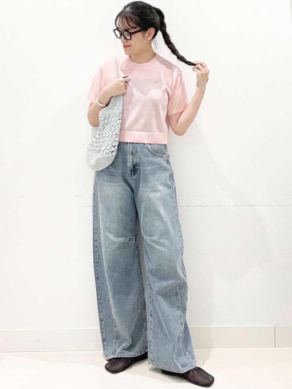 シルバー系のハンドバッグ、ブラック系のパンプス、ブルー系のデニムパンツを着用したレディースの夏コーディネートの2枚目の写真