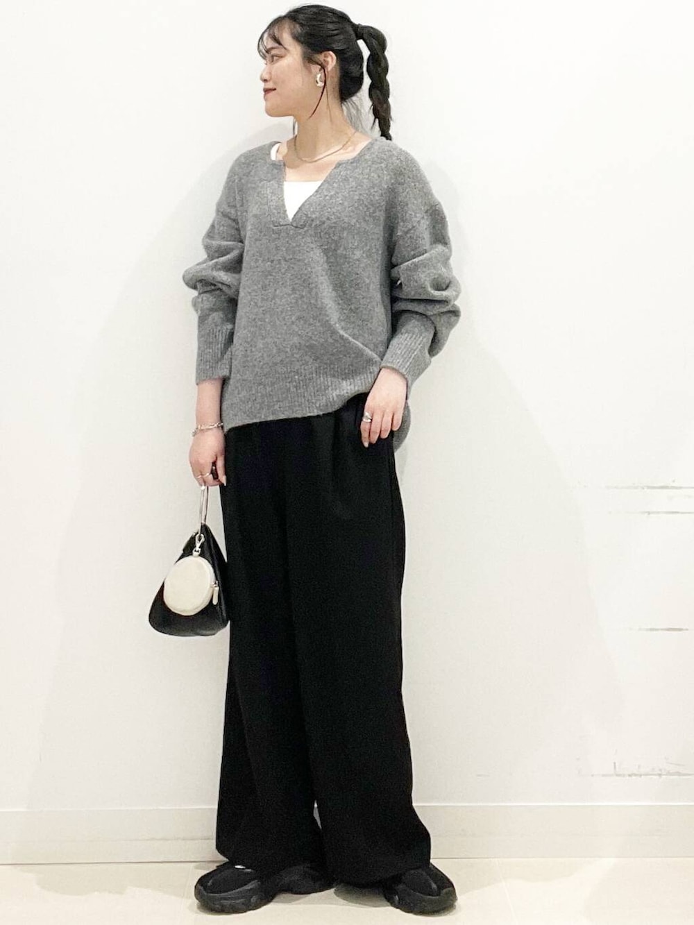 ブラック系のその他パンツ、ブラック系のスニーカー、グレー系のニット/セーターを着用したレディースの春コーディネートの3枚目の写真