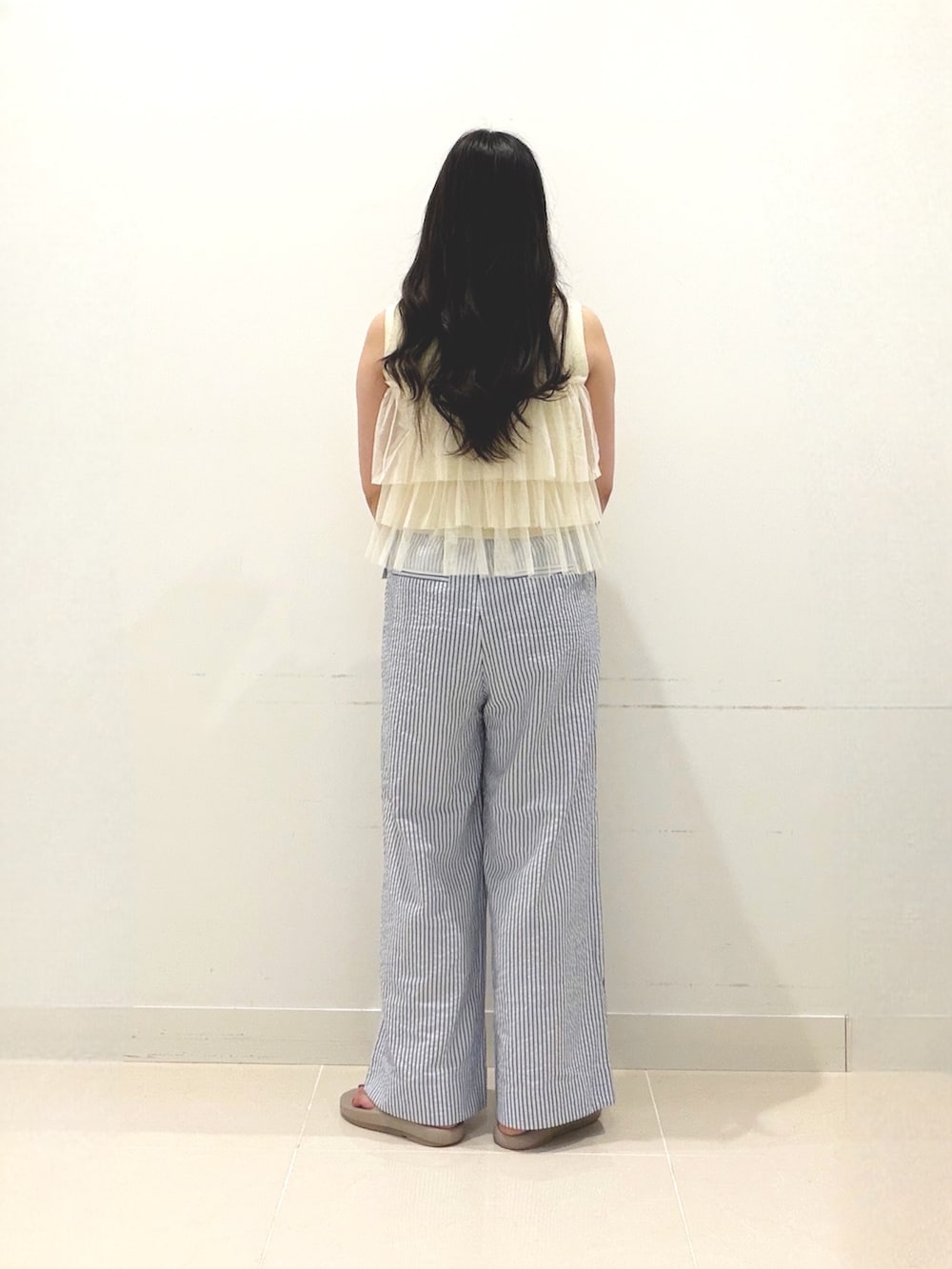 イエロー系のニット/セーター、ベージュ系のハンドバッグ、ベージュ系のサンダルを着用したレディースの夏コーディネートの5枚目の写真