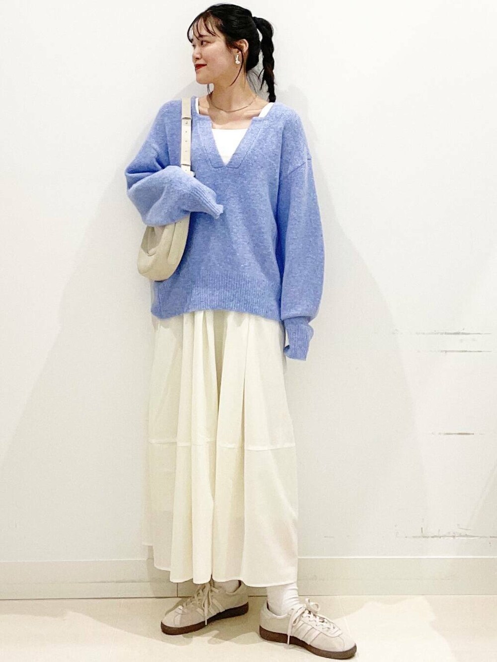 ホワイト系のスニーカー、ブルー系のニット/セーター、ベージュ系のショルダーバッグを着用したレディースの春コーディネートの4枚目の写真