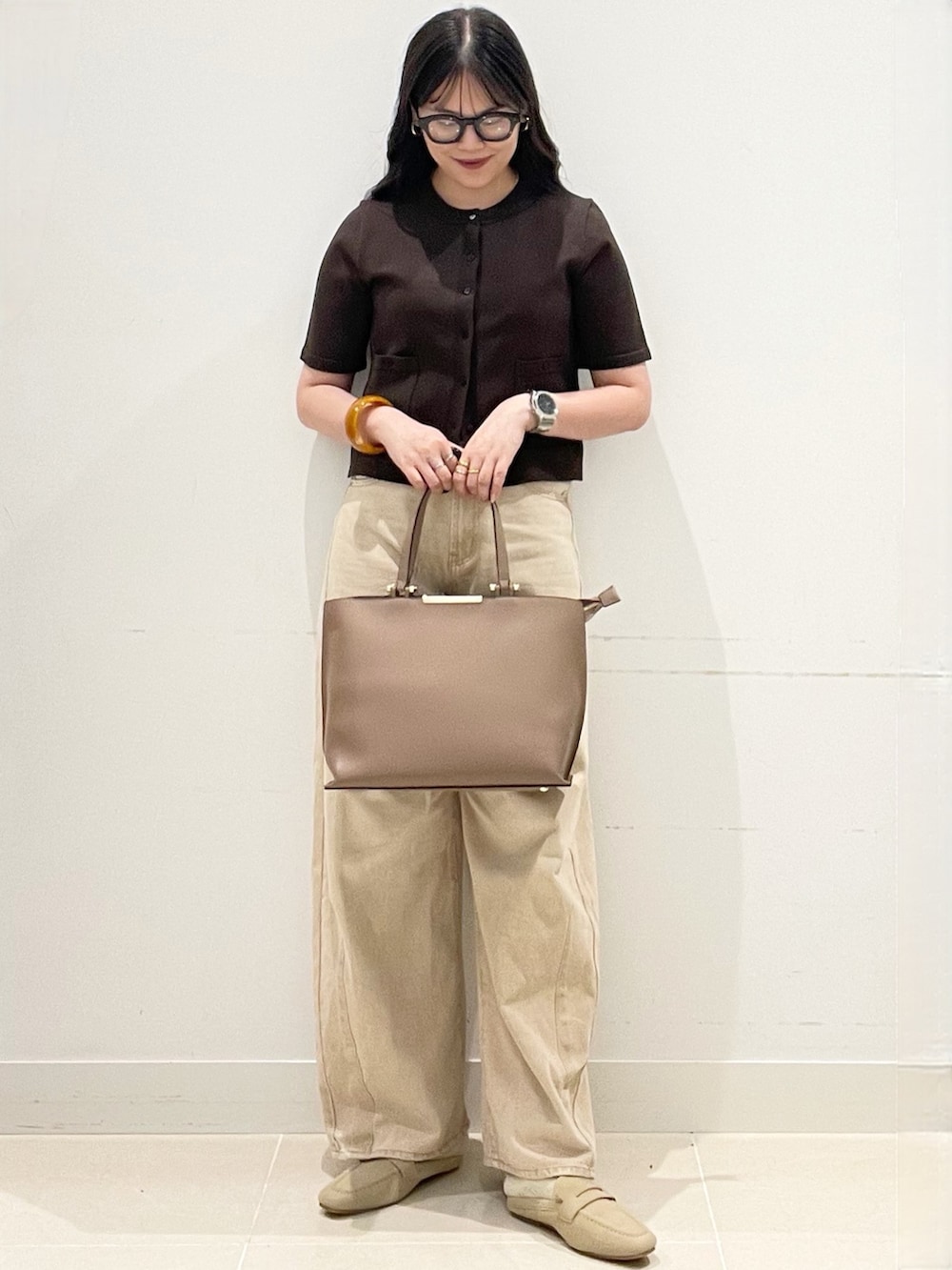 ブラウン系のカーディガン/ボレロ、ベージュ系のデニムパンツ、ブラウン系のビジネスバッグを着用したレディースの春コーディネートの2枚目の写真