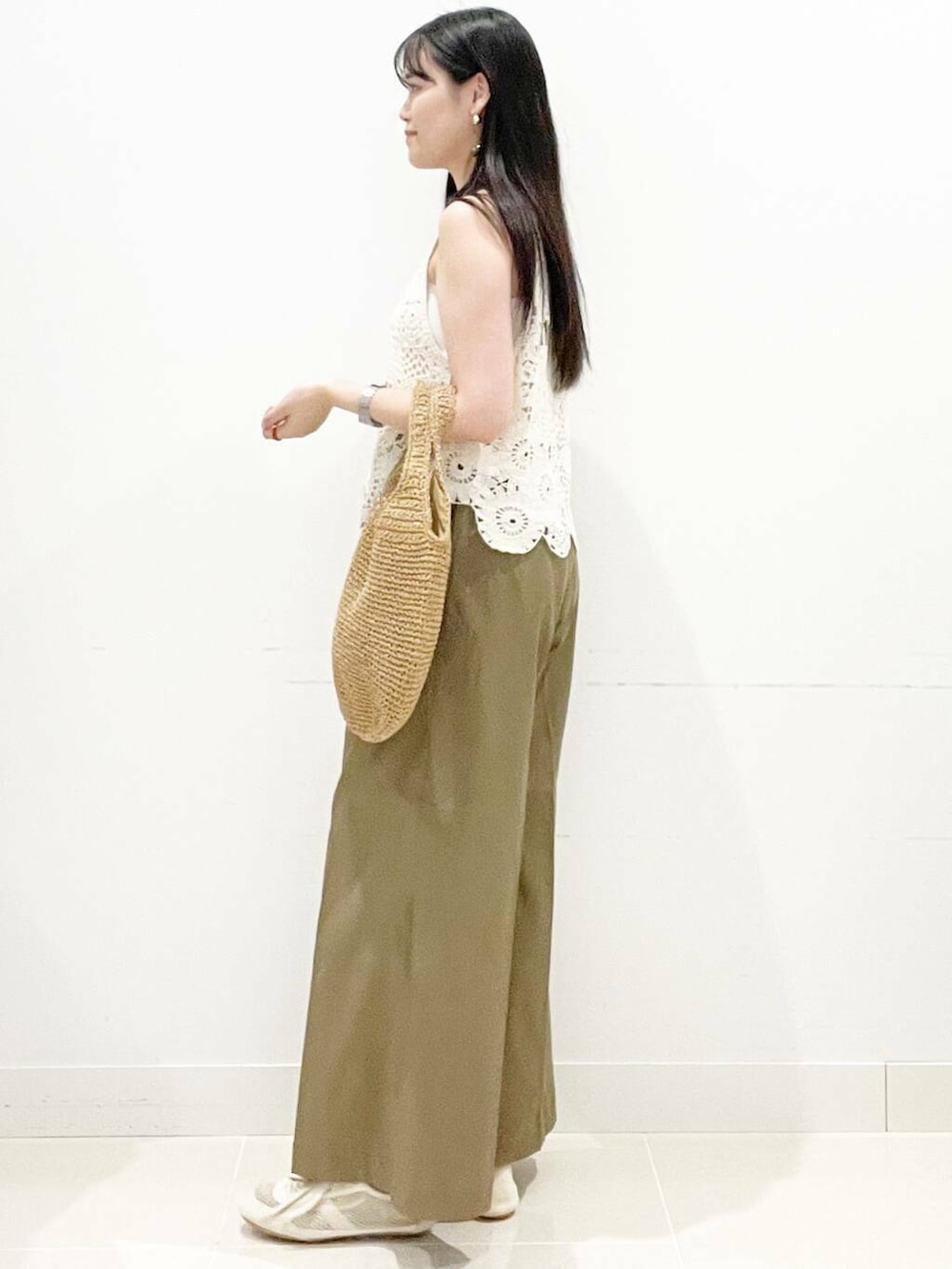 イエロー系のトートバッグ、ホワイト系のキャミソール、ホワイト系のベストを着用したレディースの夏コーディネートの6枚目の写真