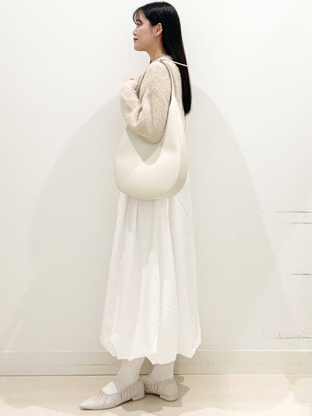 ホワイト系のスカート、ベージュ系のニット/セーター、ホワイト系のショルダーバッグを着用したレディースの冬コーディネートの4枚目の写真