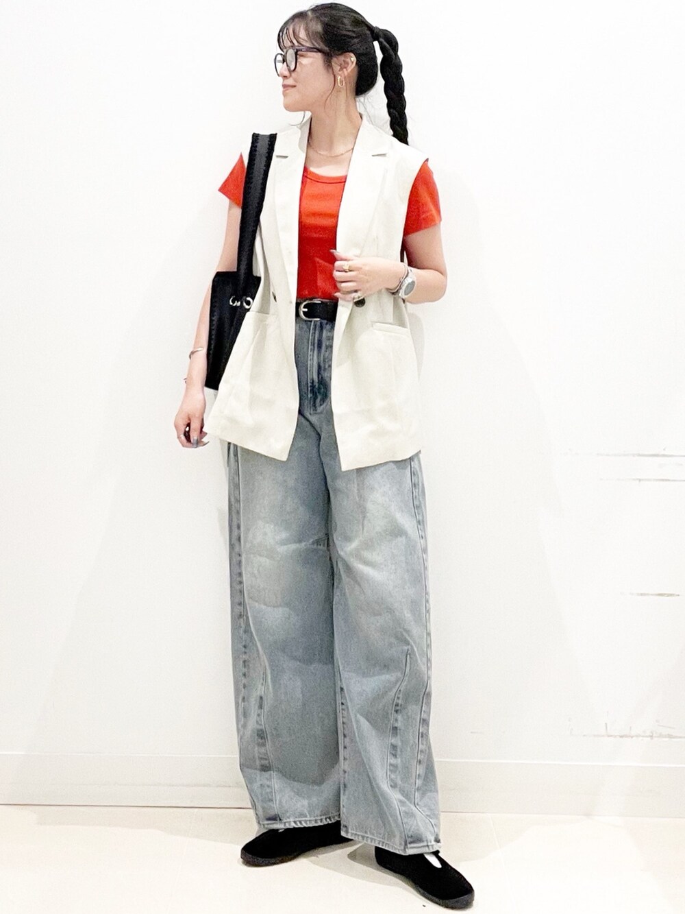 ベージュ系のベスト、レッド系のTシャツ/カットソー、ブルー系のデニムパンツを着用したレディースの夏コーディネートの2枚目の写真