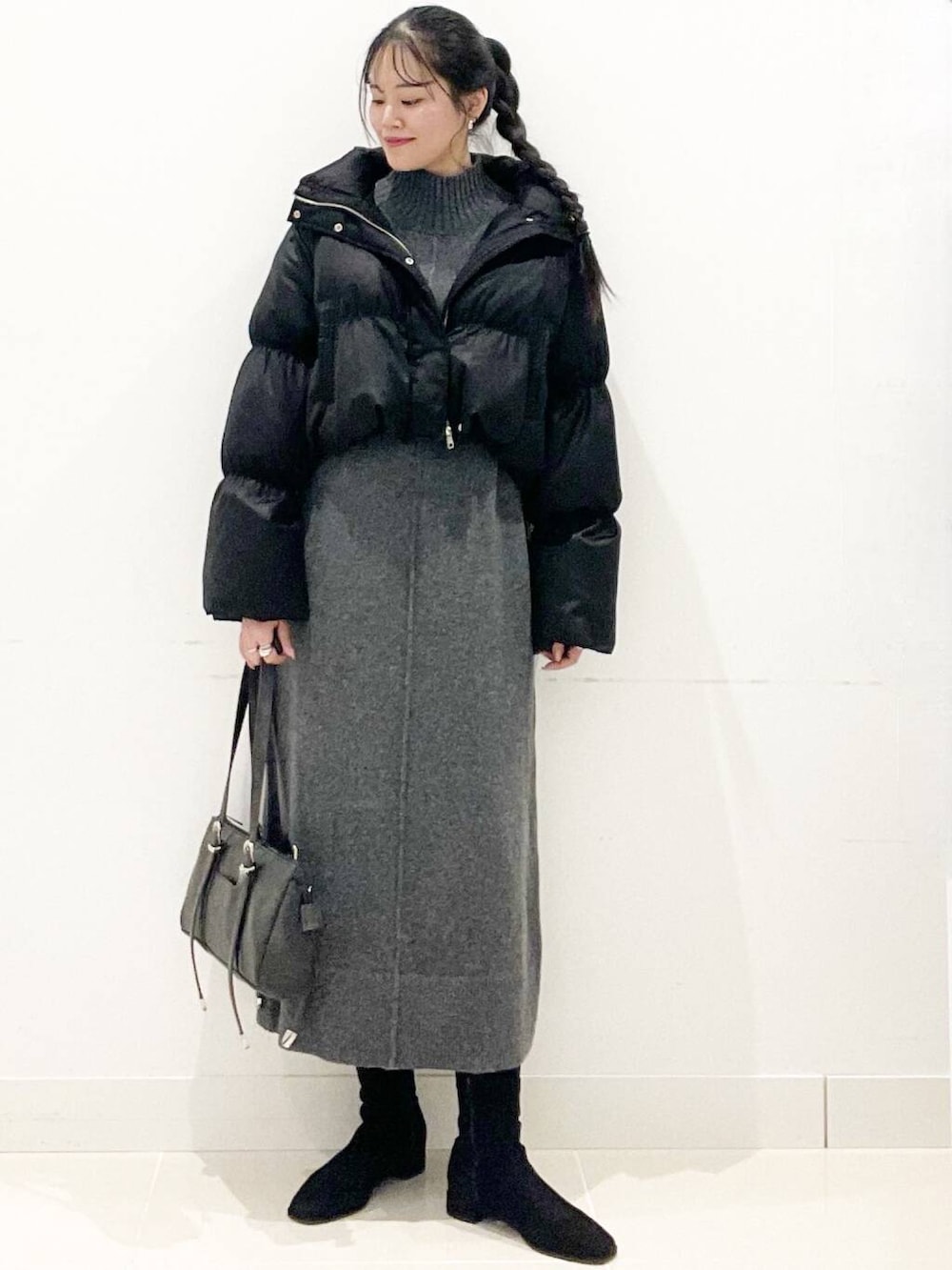 ブラック系のダウンジャケット/コート、ブラック系のブーツ、グレー系のワンピースを着用したレディースの冬コーディネートの4枚目の写真