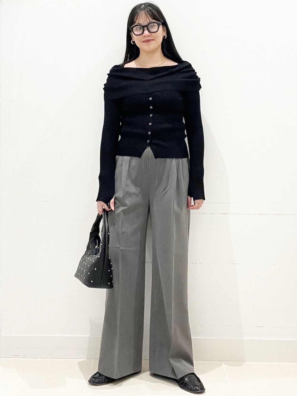 グレー系のスラックス、ブラック系のハンドバッグ、ブラック系のニット/セーターを着用したレディースの春コーディネートの3枚目の写真