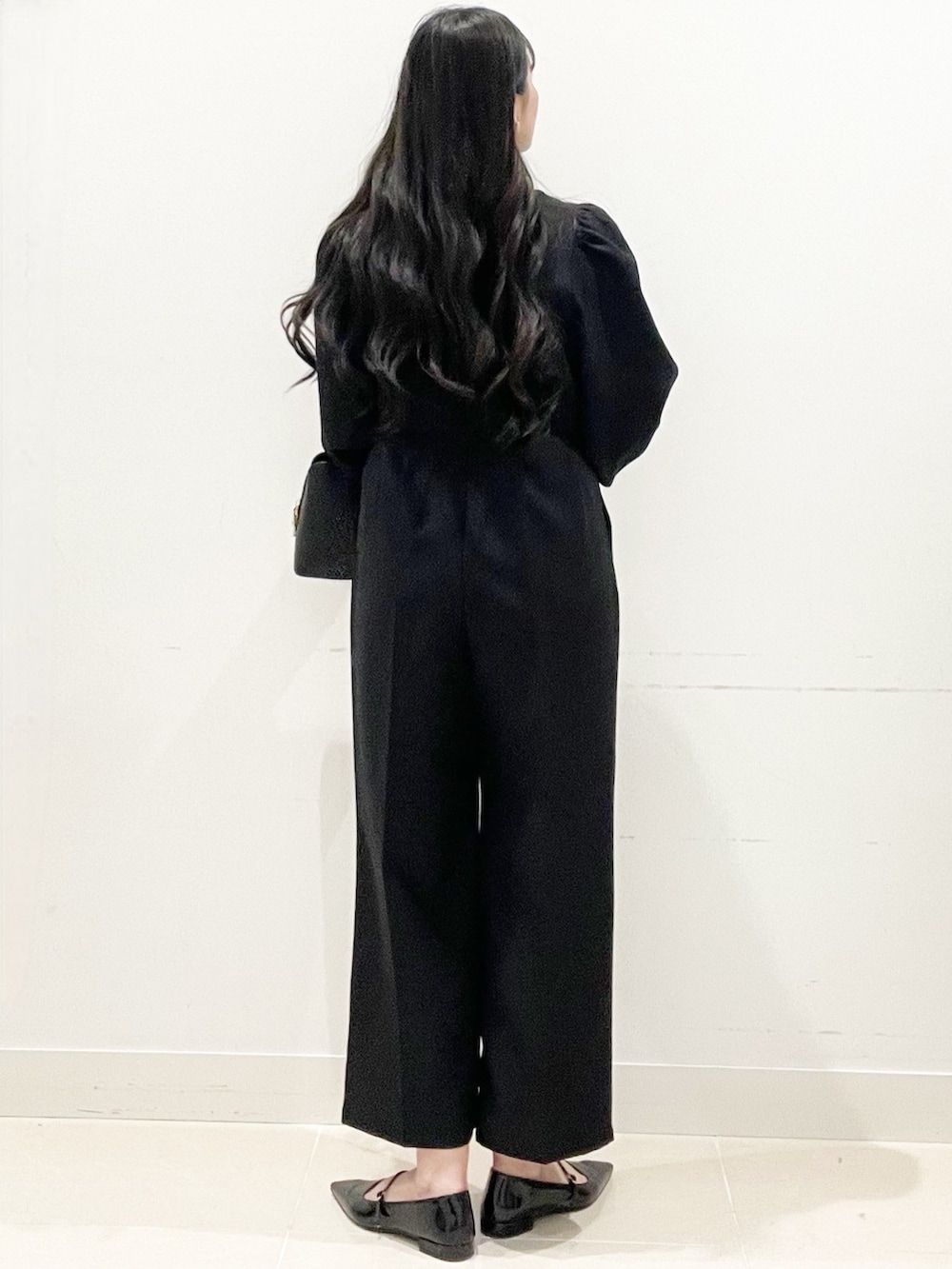 ブラック系のパンプス、ブラック系のハンドバッグ、ブラック系のつなぎ/オールインワンを着用したレディースの冬コーディネートの6枚目の写真
