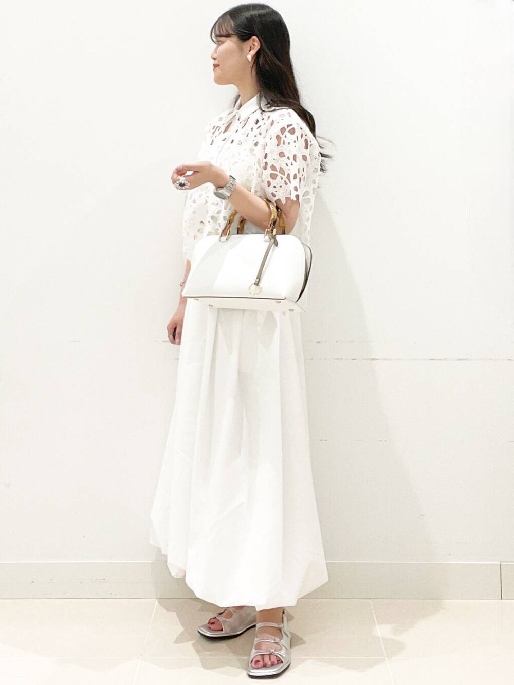 ホワイト系のスカート、ホワイト系のキャミソール、ホワイト系のハンドバッグを着用したレディースの夏コーディネートの3枚目の写真
