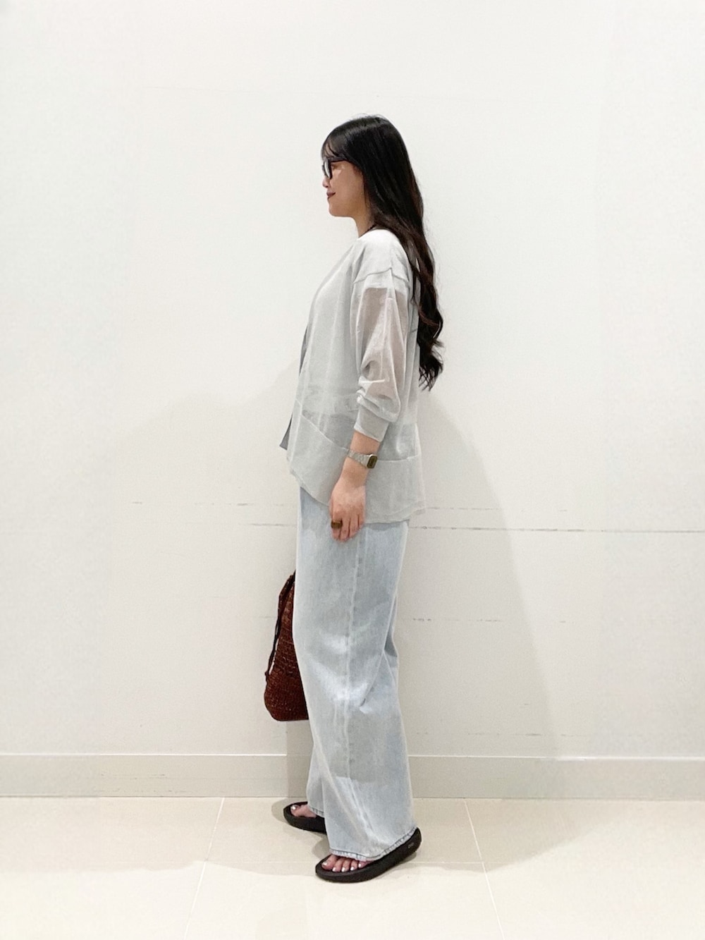 ブルー系のデニムパンツ、ブラウン系のショルダーバッグ、ブラック系のサンダルを着用したレディースの夏コーディネートの3枚目の写真