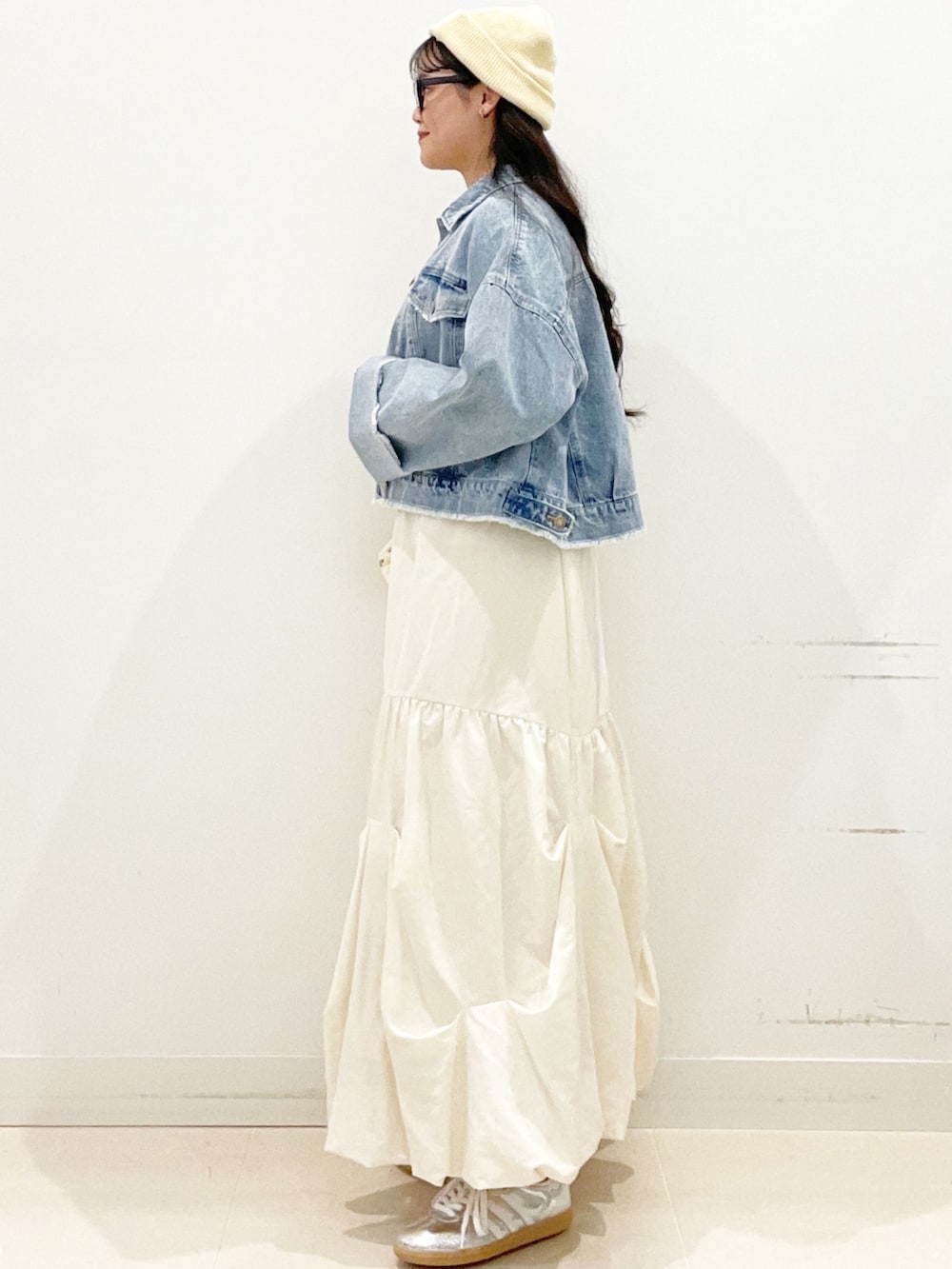 シルバー系のスニーカー、ホワイト系のスカート、ブルー系のデニムジャケットを着用したレディースの春コーディネートの4枚目の写真