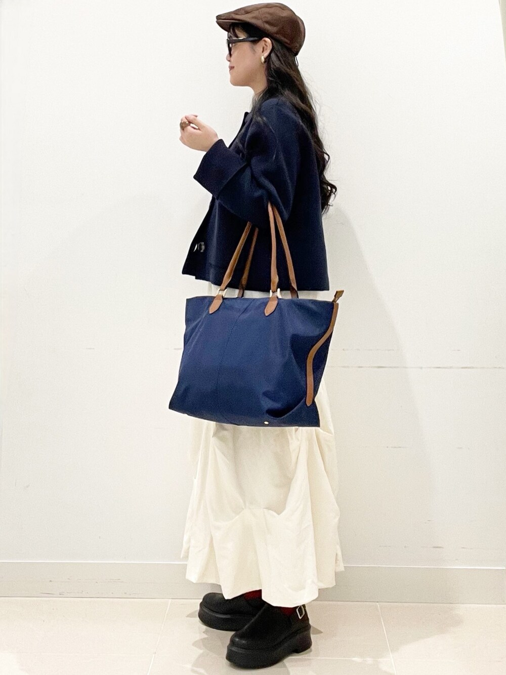 ブラック系のその他シューズ、ホワイト系のスカート、ブルー系のビジネスバッグを着用したレディースの冬コーディネートの4枚目の写真