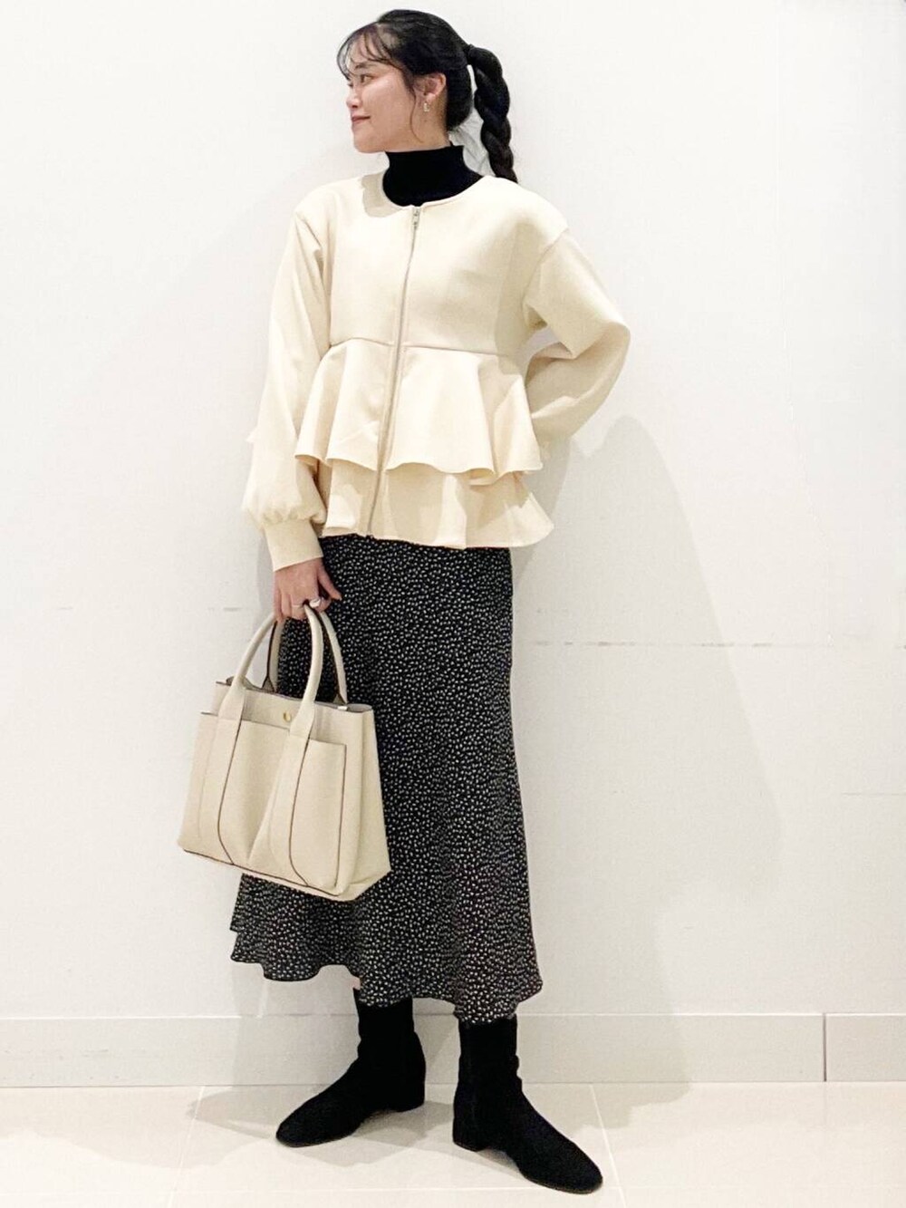 ブラック系のニット/セーター、ブラック系のブーツ、ホワイト系のトートバッグを着用したレディースの冬コーディネートの3枚目の写真
