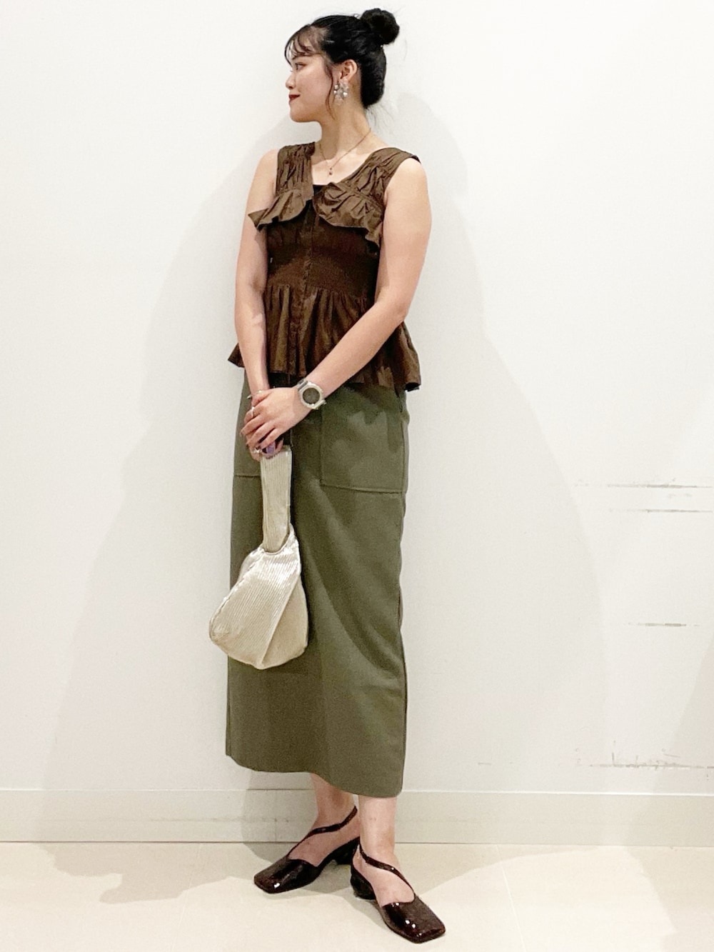 グリーン系のスカート、ブラック系のキャミソール、ゴールド系のハンドバッグを着用したレディースの夏コーディネートの2枚目の写真