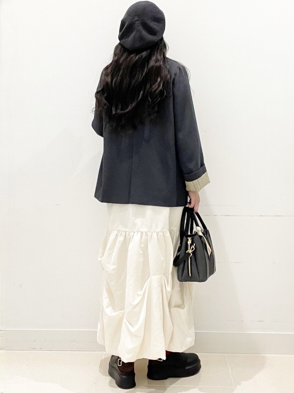 ブラック系のその他シューズ、ブラック系のハンドバッグ、ホワイト系のスカートを着用したレディースの冬コーディネートの6枚目の写真