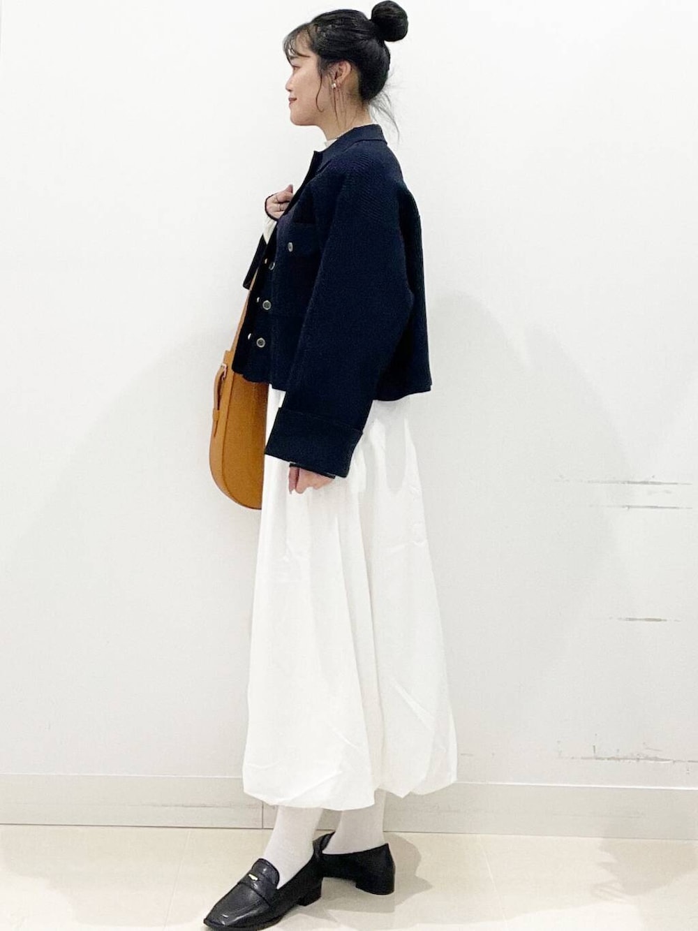 ホワイト系のスカート、ブラウン系のショルダーバッグ、ブラック系のローファーを着用したレディースの冬コーディネートの6枚目の写真