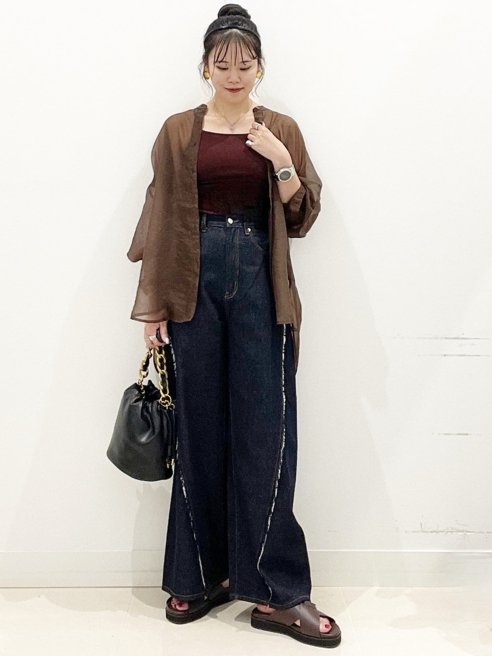 ブラウン系のサンダル、ブルー系のデニムパンツ、ブラック系のショルダーバッグを着用したレディースの夏コーディネートの3枚目の写真