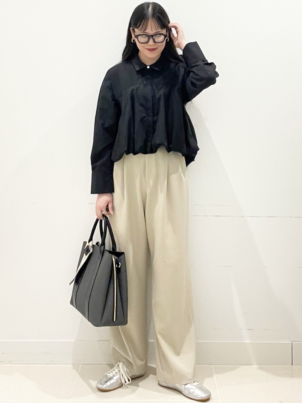 ベージュ系のスラックス、ブラック系のシャツ/ブラウス、ブラック系のトートバッグを着用したレディースの春コーディネートの3枚目の写真