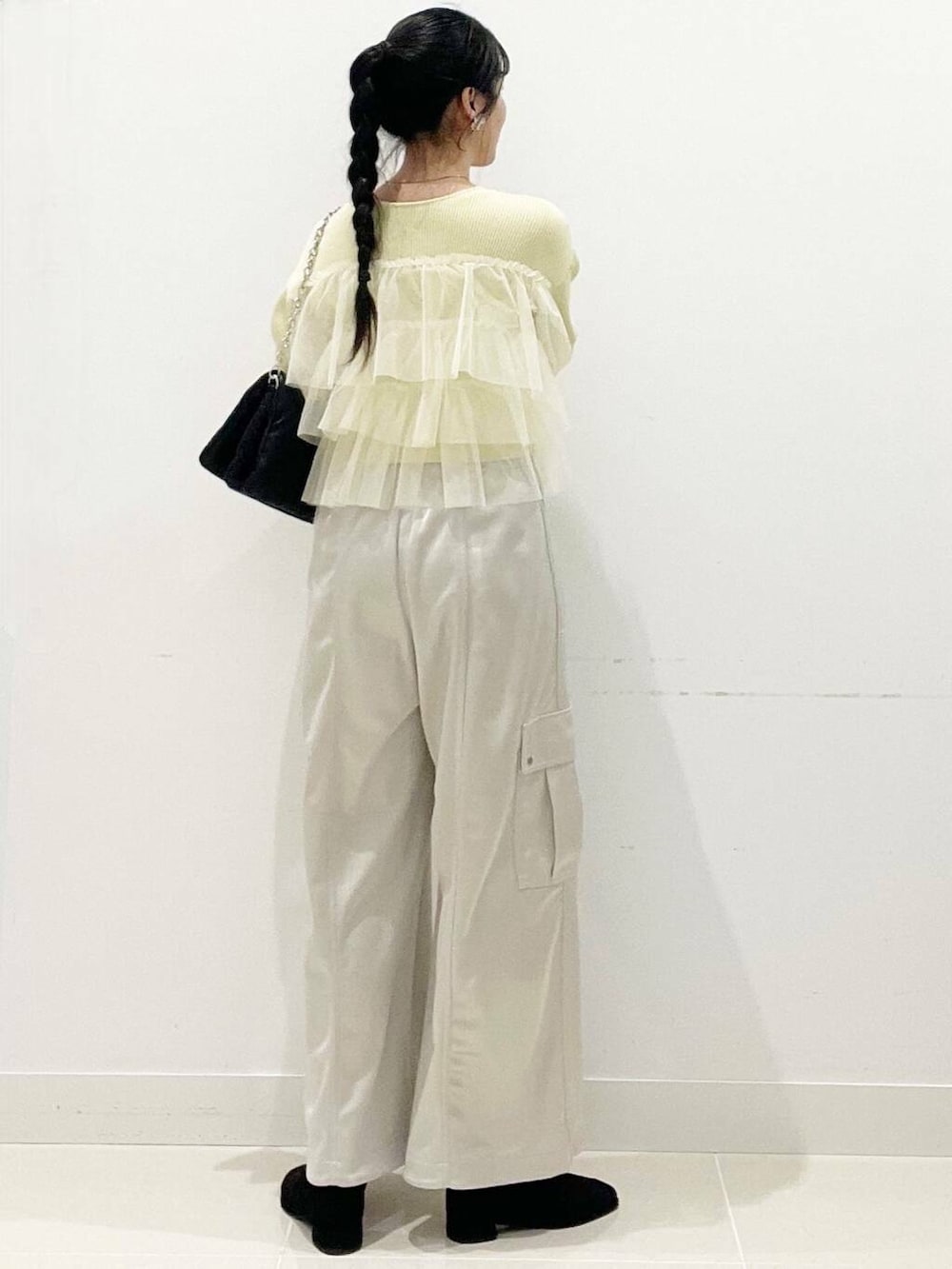 ブラック系のブーツ、ブラック系のショルダーバッグ、イエロー系のニット/セーターを着用したレディースの冬コーディネートの7枚目の写真