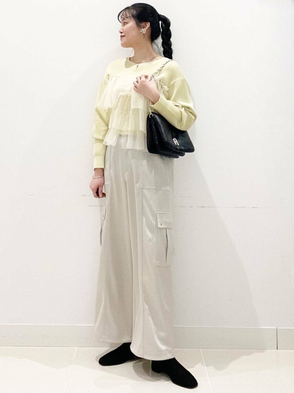 ブラック系のブーツ、ブラック系のショルダーバッグ、イエロー系のニット/セーターを着用したレディースの冬コーディネートの2枚目の写真